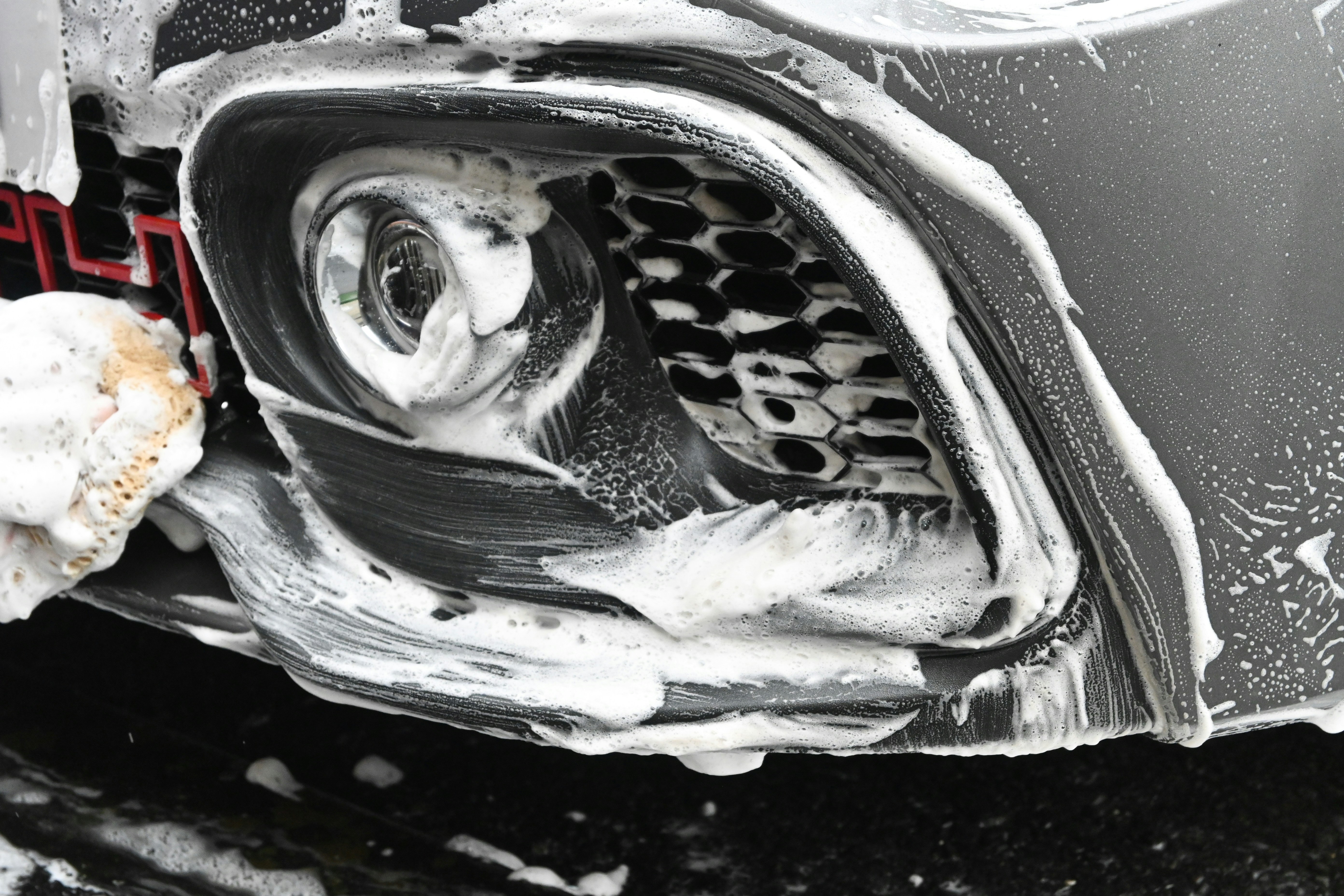 Soapy foam on car headlight during exterior detail